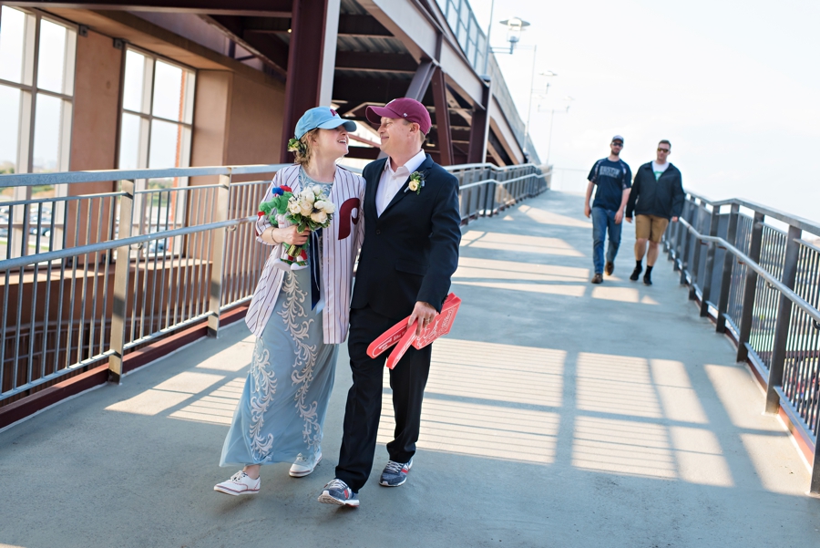 A bride and groom walk to their reception suite at a Phillies game on their wedding day.